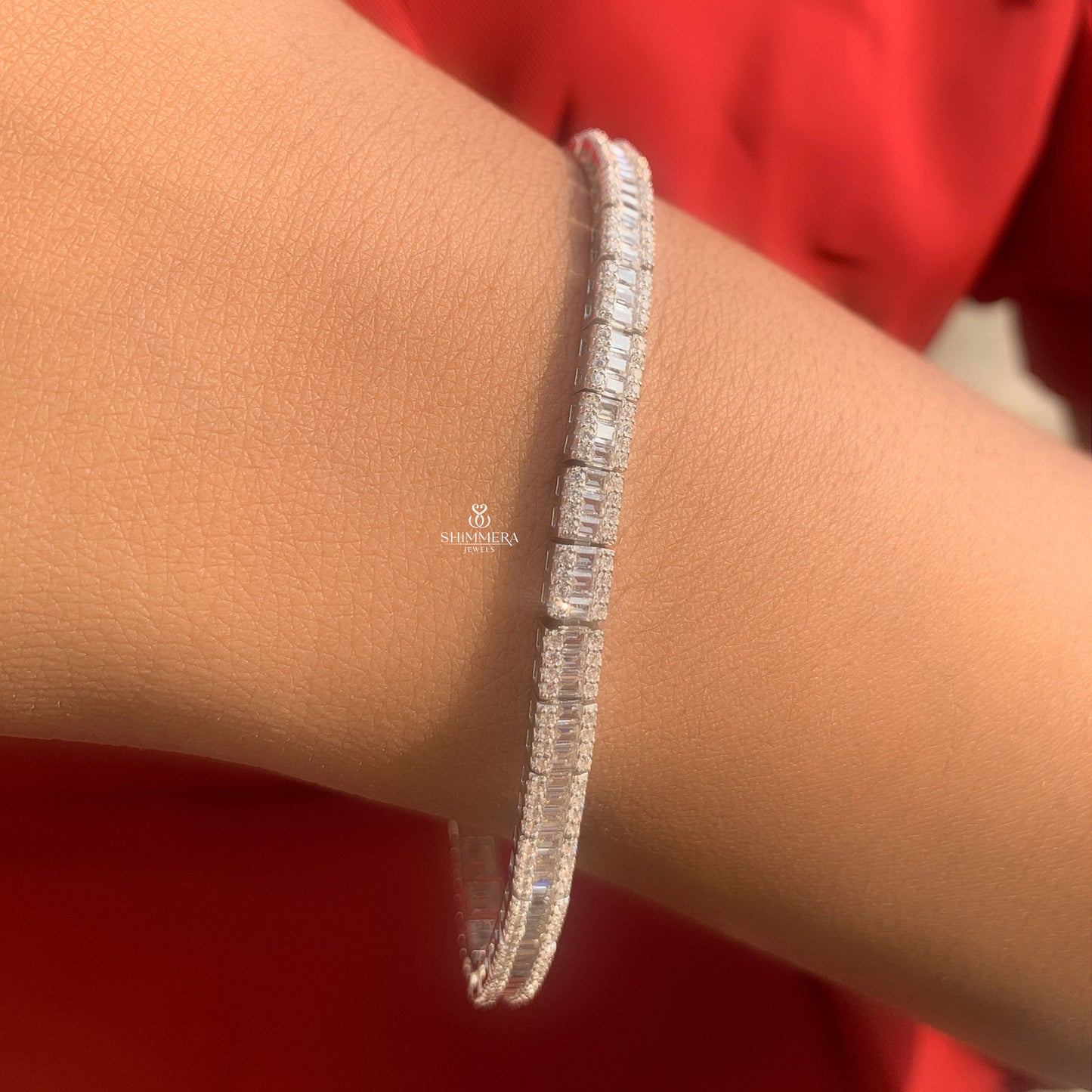 Silver bracelet on a wrist with a red background
