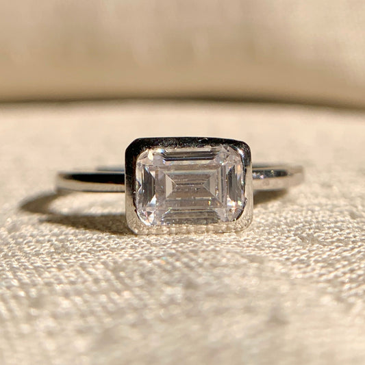“Emerald cut east-west solitaire engagement ring in sleek white gold setting”