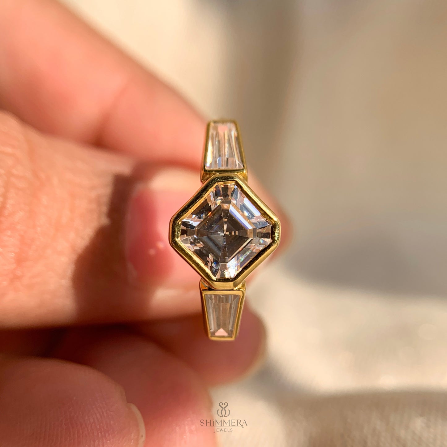 Bezel set Asscher diamond with baguette side stones in a three stone design