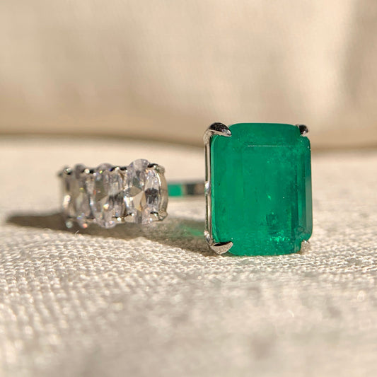 “Emerald and oval diamond open band wedding ring in polished gold setting”