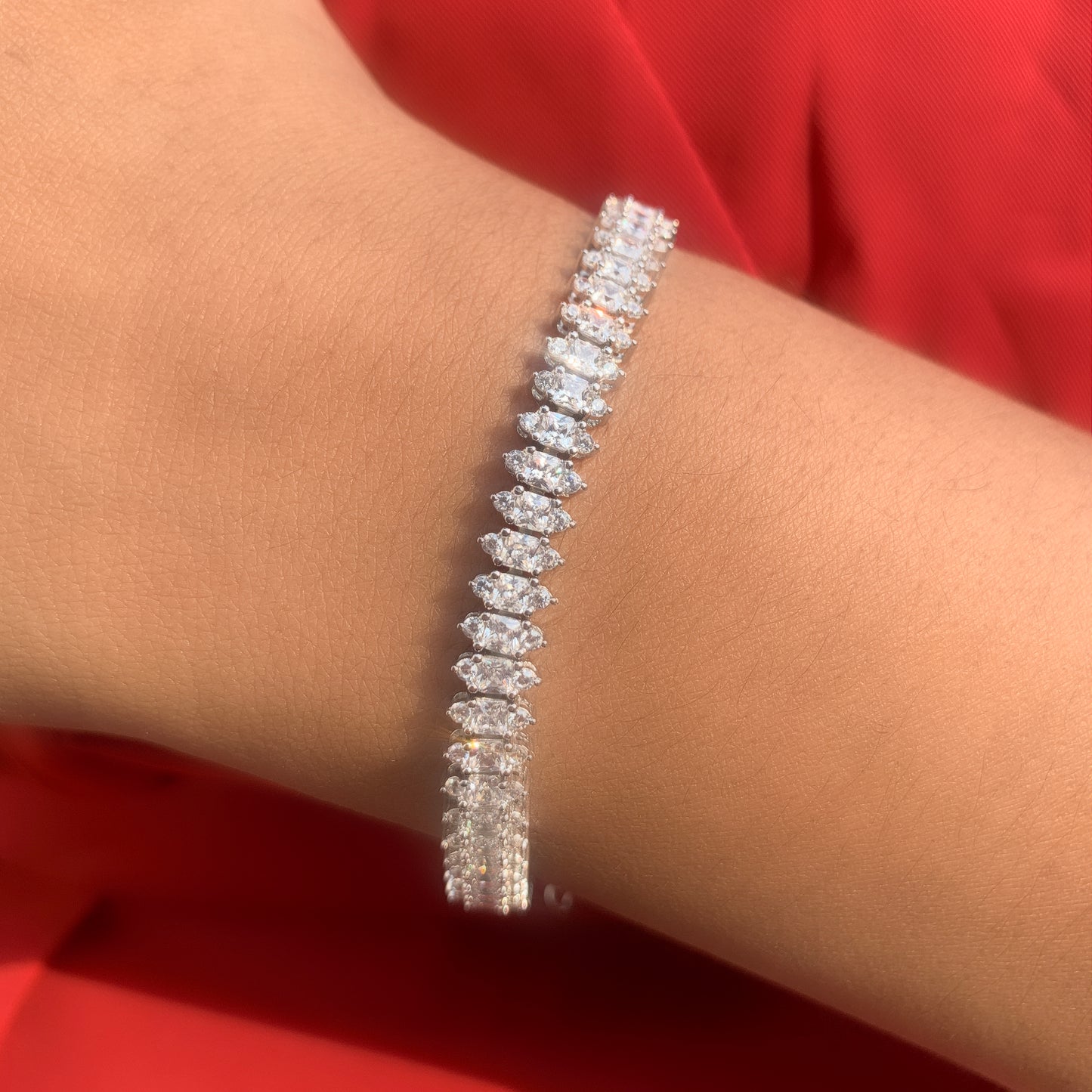 Diamond bracelet on a wrist with a red background