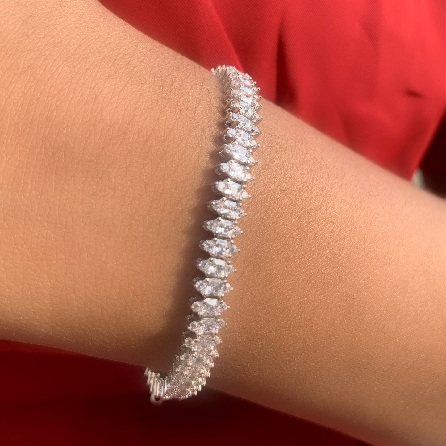 Silver bracelet on a wrist with a red background