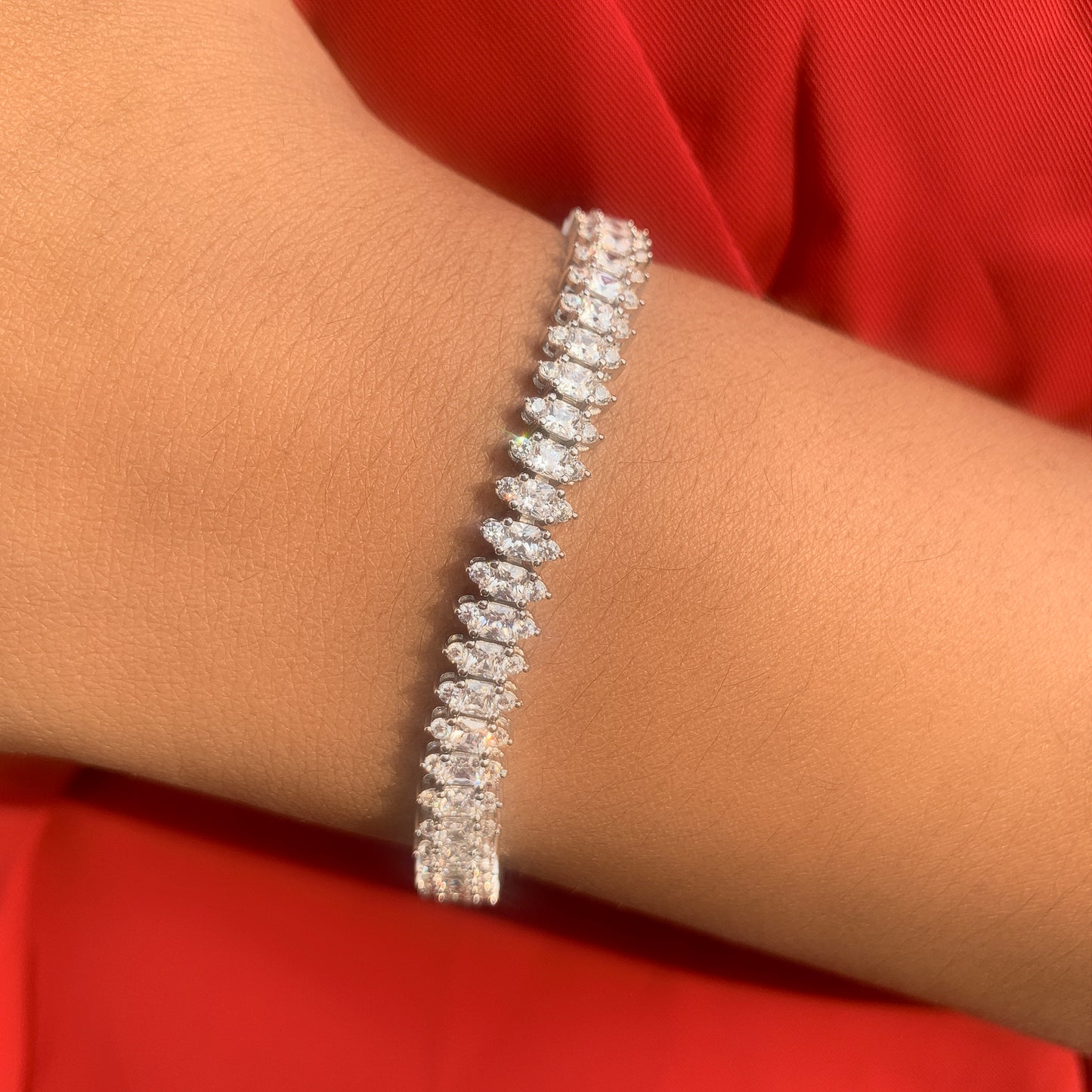 Silver bracelet on a person's wrist with a red fabric background