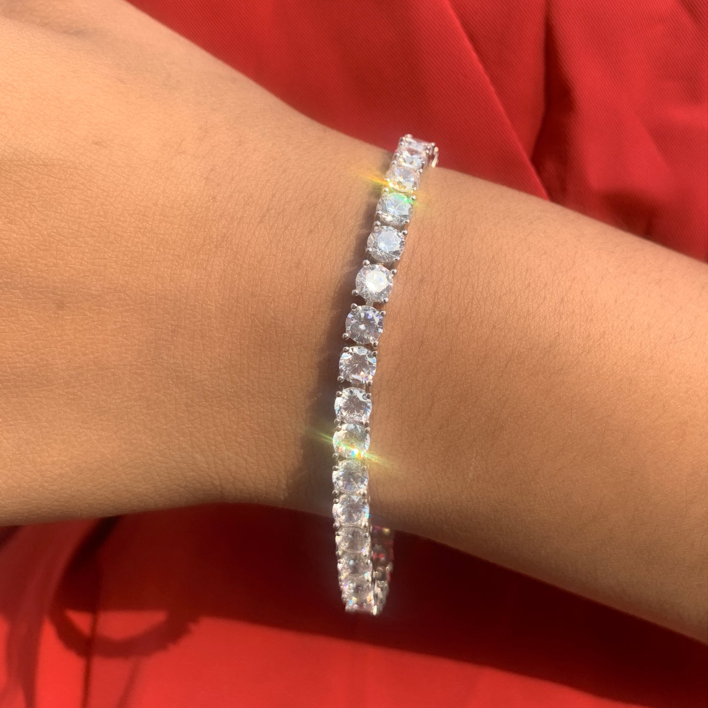 Diamond bracelet on a wrist against a red background