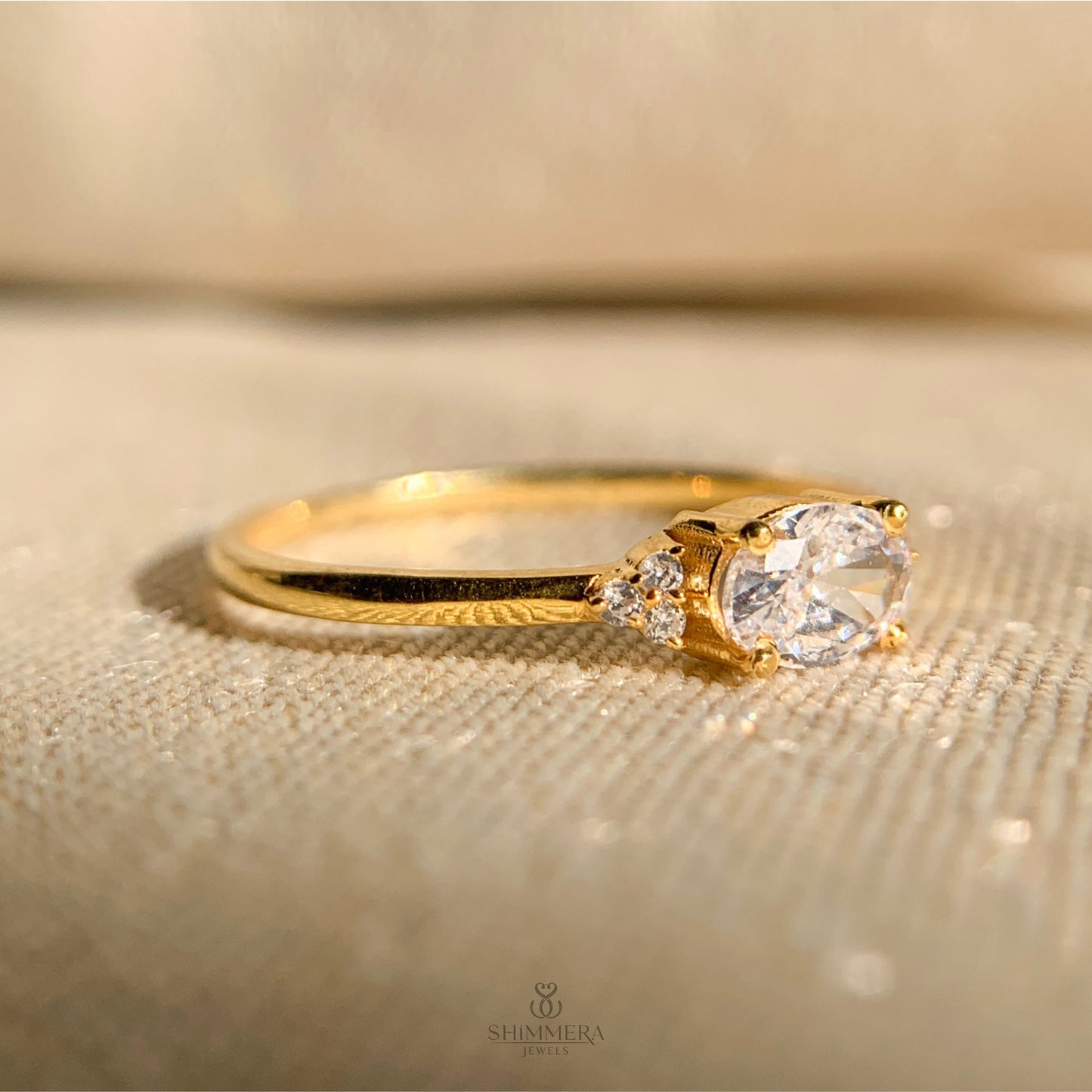 Contemporary gold engagement ring with east west oval diamond