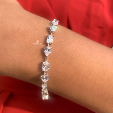 Silver bracelet with clear stones on a wrist against a red background