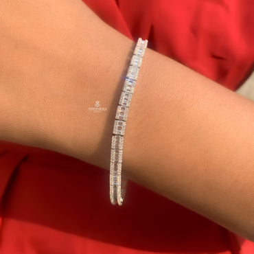 Silver bracelet with clear stones on a wrist against a red background