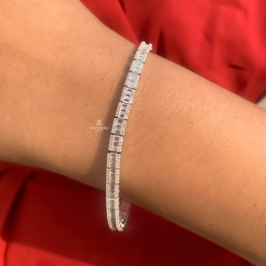 Silver bracelet with clear stones on a wrist against a red background
