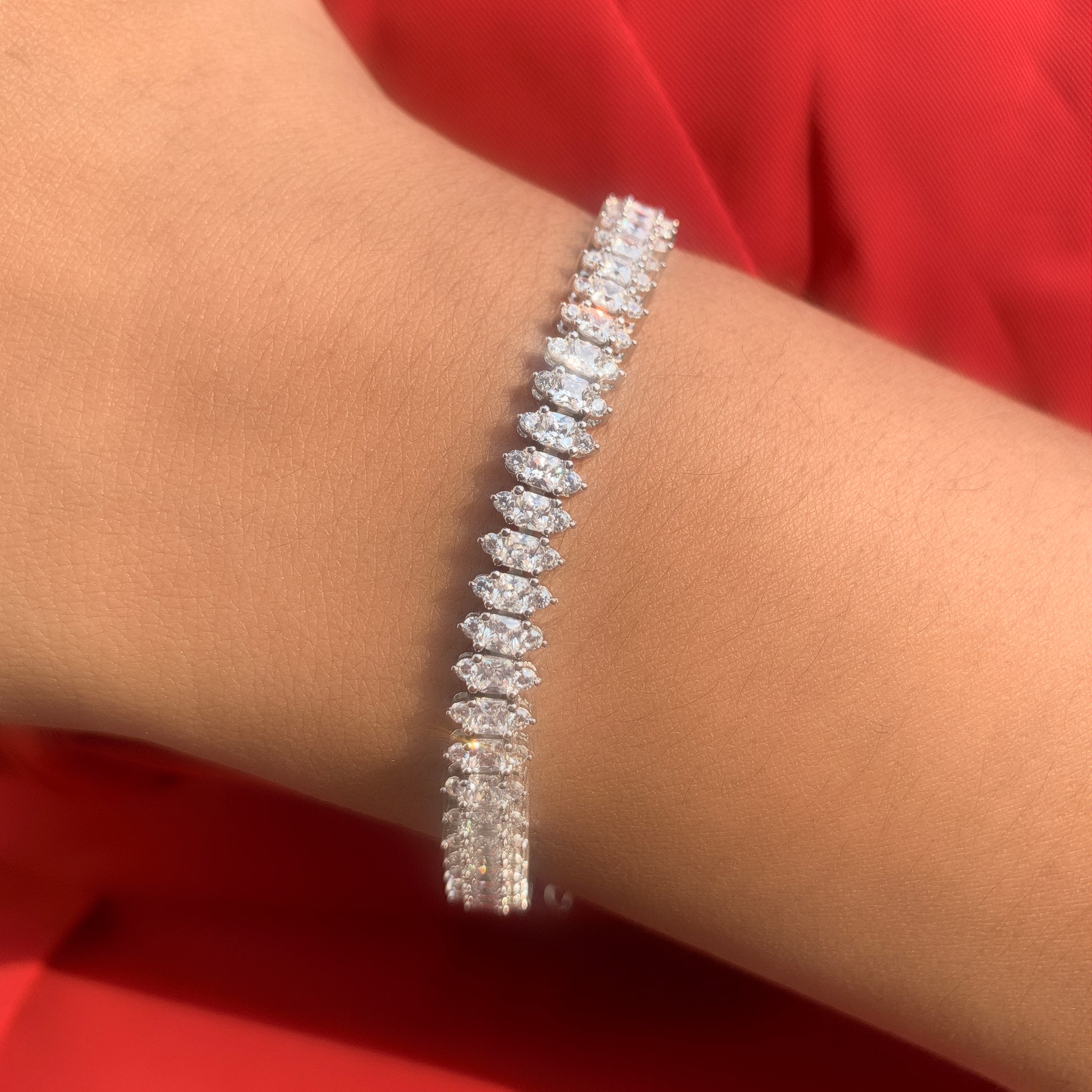 Diamond bracelet on a wrist with a red background