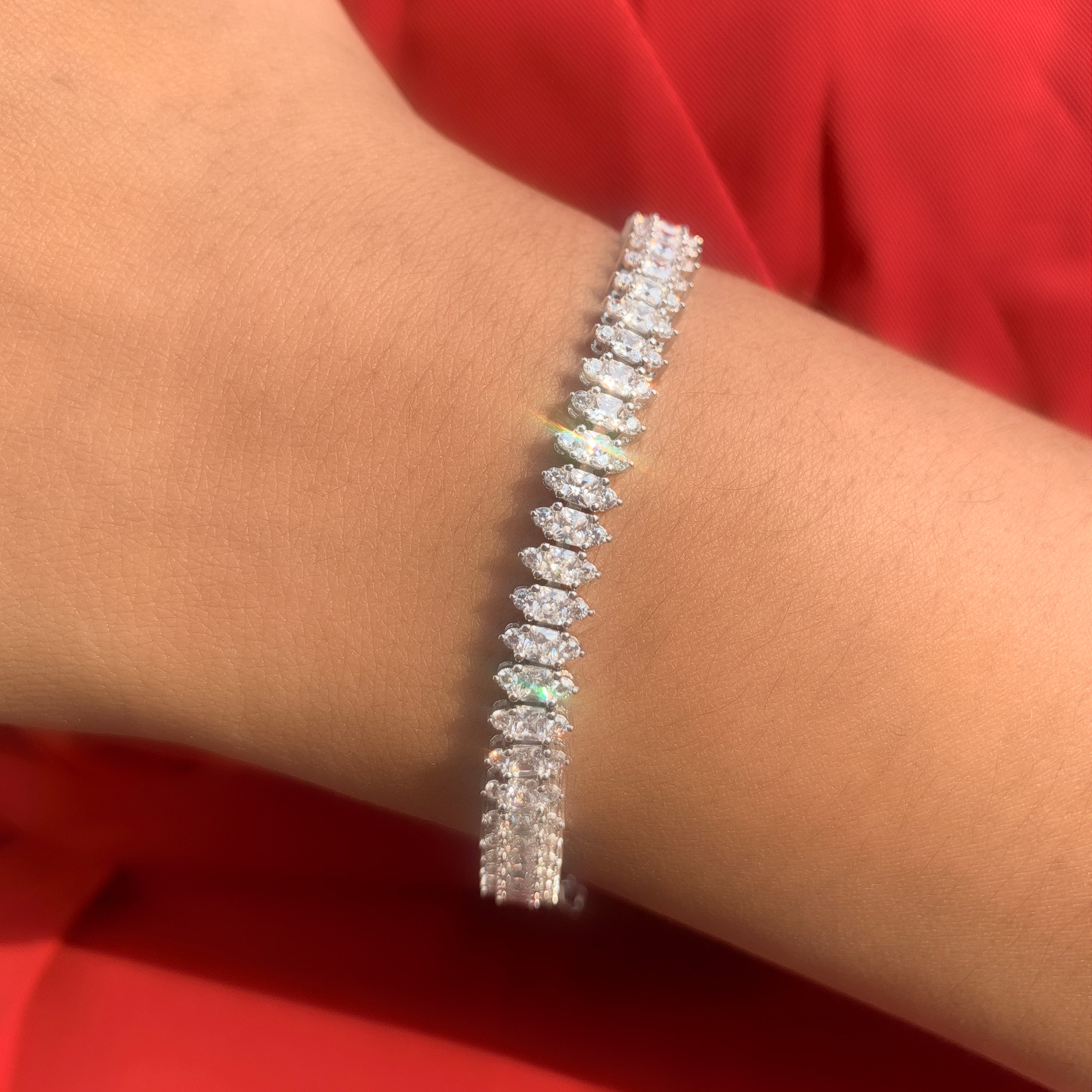 Diamond bracelet on a person's wrist with a red background