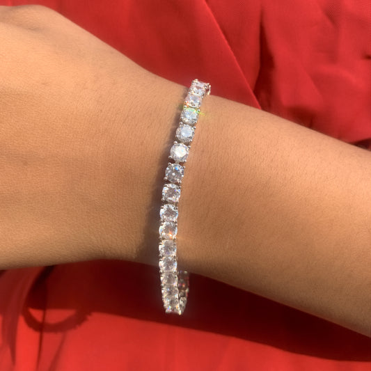 Silver bracelet with clear stones on a wrist against a red background